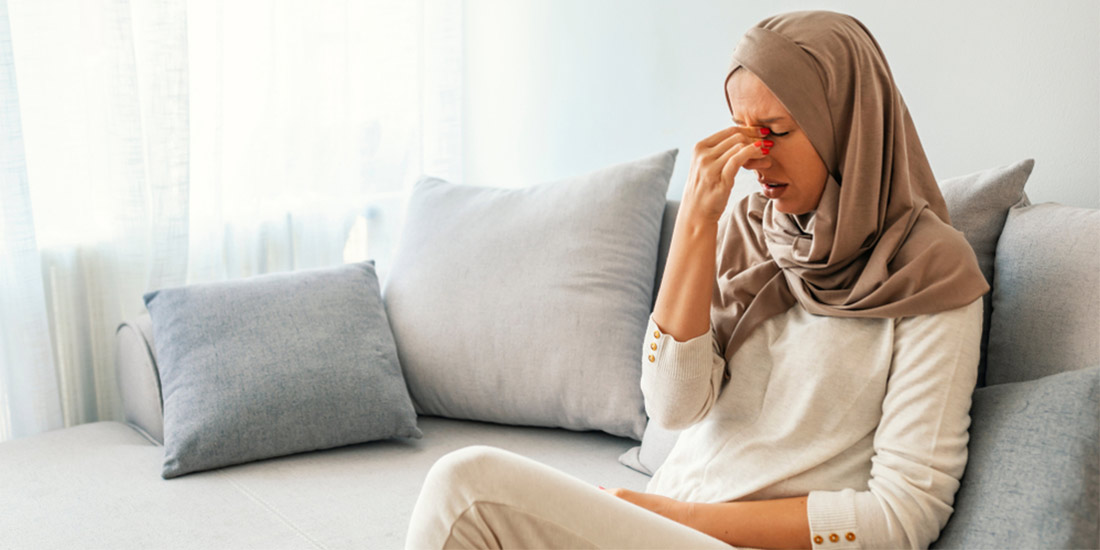 woman wearing scarf holding nose with the sinus infection contagious pain