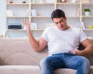man holding stomach thinking how to lose weight with hypothyroidism
